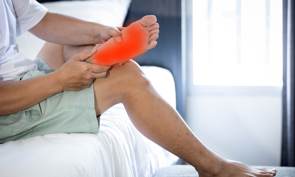 A man sitting down, experiencing bottom of foot pain.