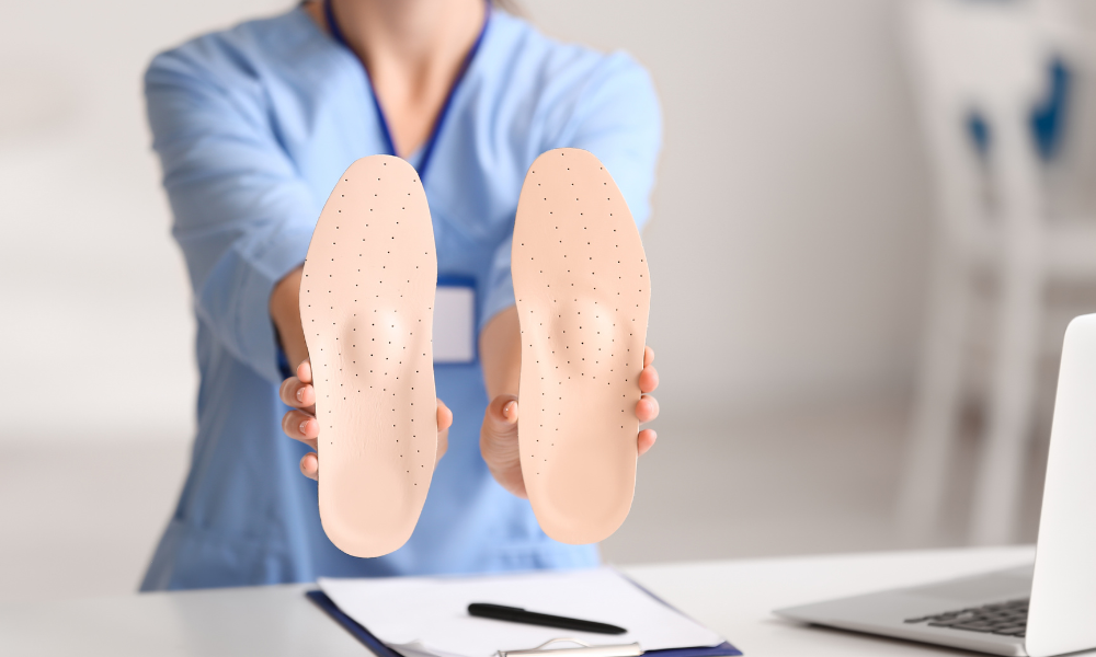a image of a female doctor holding a pair of orthotics out in front of her to show how orthotics help