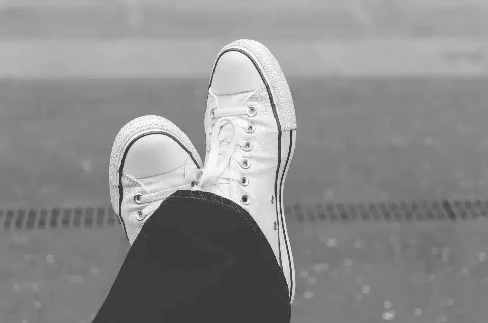 White converse with a gray background. Someone wonders if they underpronate or overpronate.