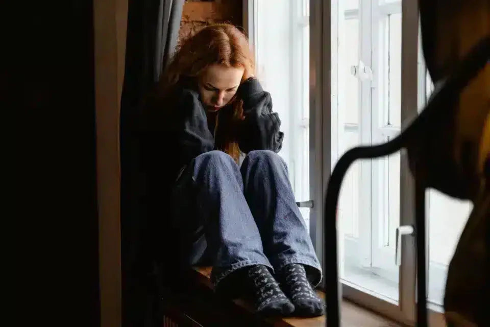 Woman sitting on window seal with fibromyalgia foot pain.