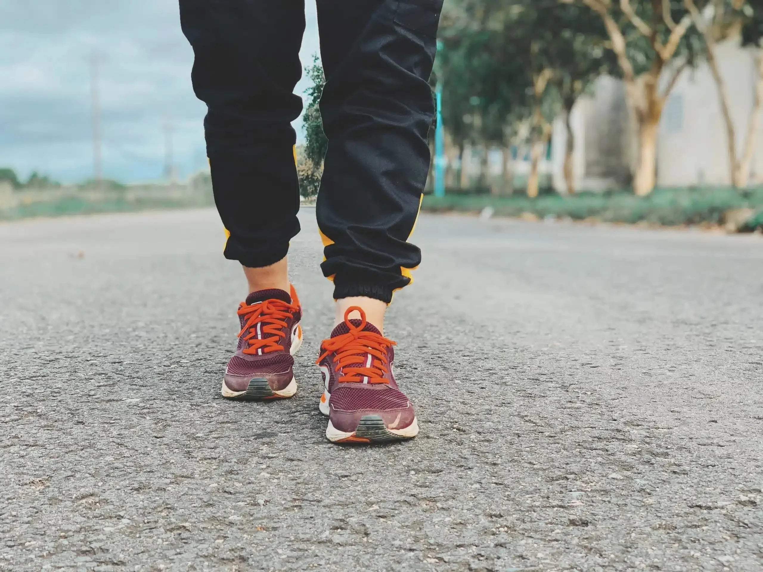 A woman walking on the road with red shoelaces.