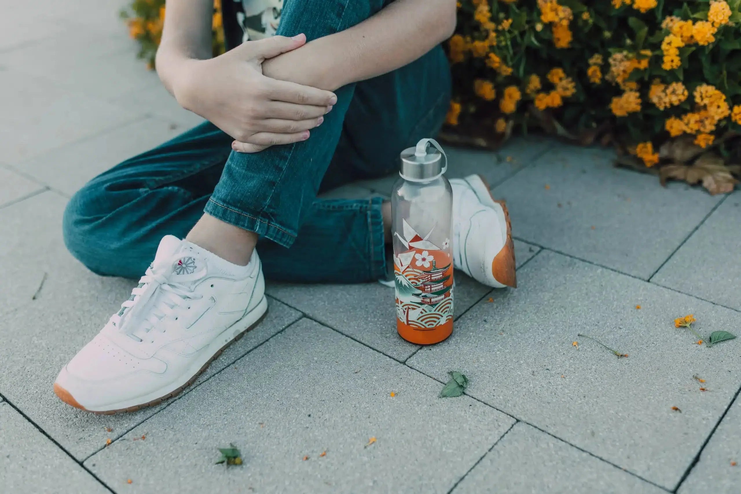 Sitting with a water bottle and flowers with the best arch supports for flat feet.