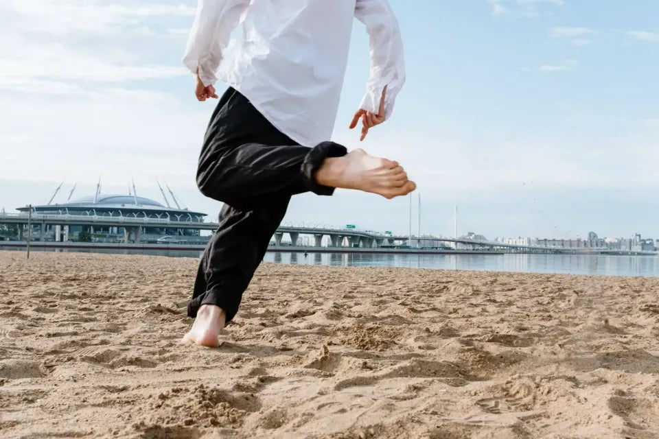 A man with foot tendonitis running barefoot on the beach.