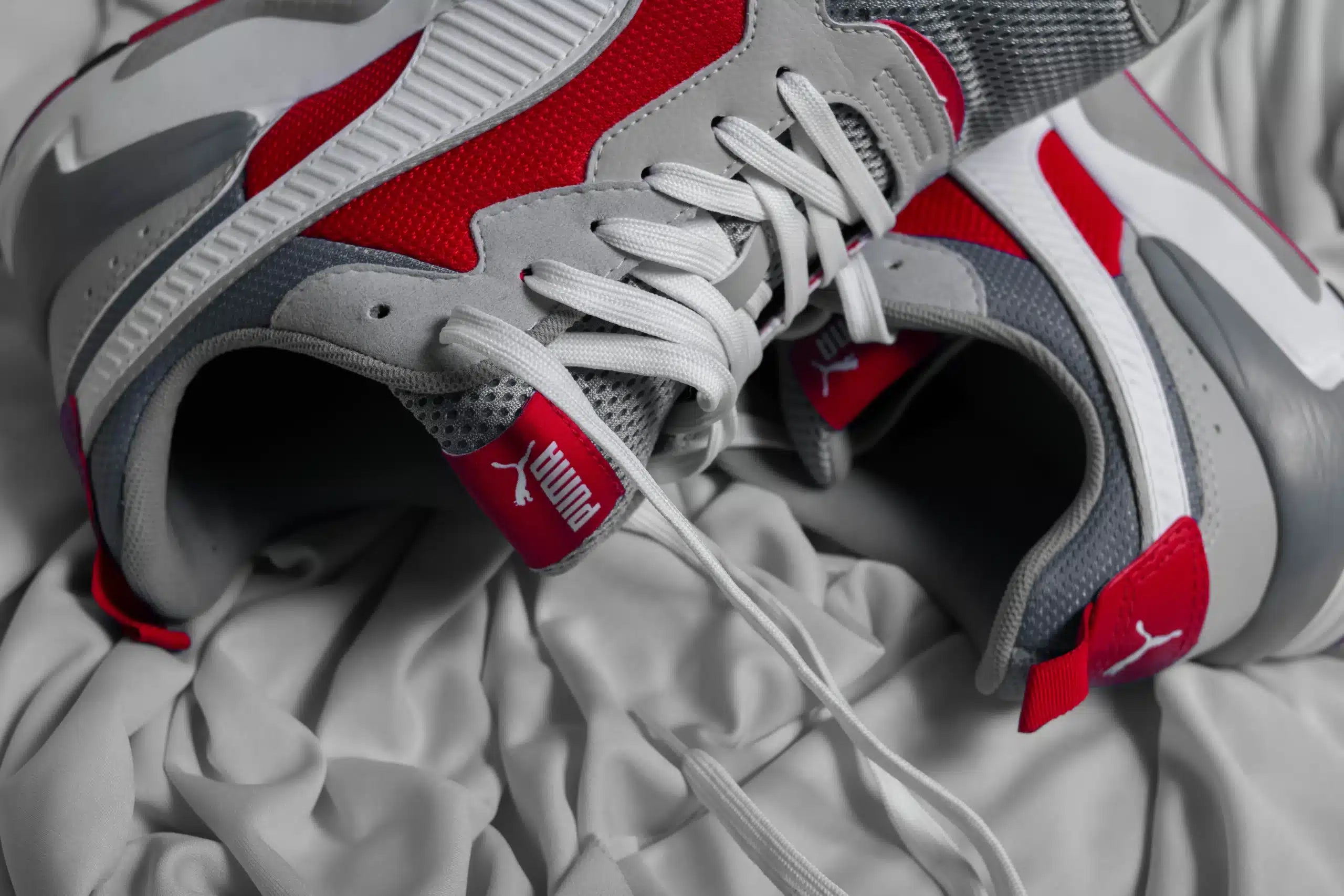 Red and gray sneakers on a bed. They have the best insoles for plantar fasciitis.